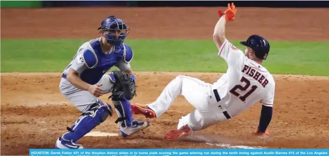  ??  ?? HOUSTON: Derek Fisher #21 of the Houston Astros slides in to home plate scoring the game winning run during the tenth inning against Austin Barnes #15 of the Los Angeles Dodgers in game five of the 2017 World Series at Minute Maid Park yesterday.—AFP