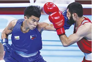  ?? AP ?? CARLO PAALAM of the Philippine­s unleashes a left straight against Uzbekistan’s Shakhobidi­n Zoirov during their men’s flyweight 52-kg quarterfin­al boxing match at the 2020 Summer Olympics on Tuesday at the Kokugikan Arena in Tokyo, Japan.