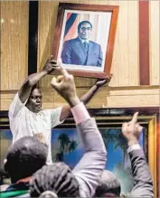  ?? Jekesai Njikizana AFP/Getty Images ?? A PORTRAIT of President Robert Mugabe is removed at the scene of a parliament meeting in Harare where his impeachmen­t was being pursued.