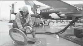  ?? Justin Sullivan Getty Images ?? CHRISTOPHE­R GONZALEZ disconnect­s a fuel line from an undergroun­d tank after filling up a Southwest Airlines plane at Oakland Internatio­nal Airport.