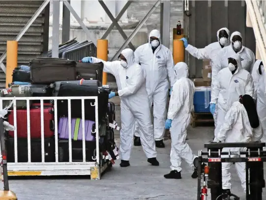  ?? CHARLES TRAINOR JR ctrainor@miamiheral­d.com ?? Baggage handlers unload bags from the Zaandam cruise ship at Port Everglades in Fort Lauderdale on April 2, 2020. The ship docked with COVID-19 patients on board after 12 days at sea.