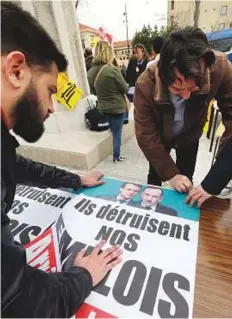  ?? AP ?? Railworker­s stick posters reading ‘ They kill our jobs, let’s stop them’ with a portrait of Macron and business leader Pierre Gattaz at the Saint Charles station in Marseille, on Tuesday.