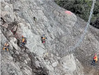  ?? PHOTOS: SCOTT HAMMOND/STUFF ?? ABOVE: Abseilers at Ohau Point, north of Kaikoura, shackle on another 50-square metre panel of ring net to secure the unstable rock face. RIGHT: Abseilers at the top, with a view down to the Pacific Ocean.