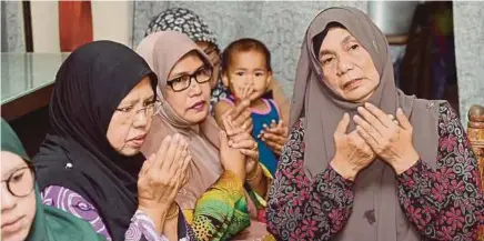  ?? BERNAMA PIC ?? Iza Karmila Ramli’s mother, Maznah Adnan (right), and family members during a ‘doa selamat’ ceremony in Sitiawan, Perak, yesterday.