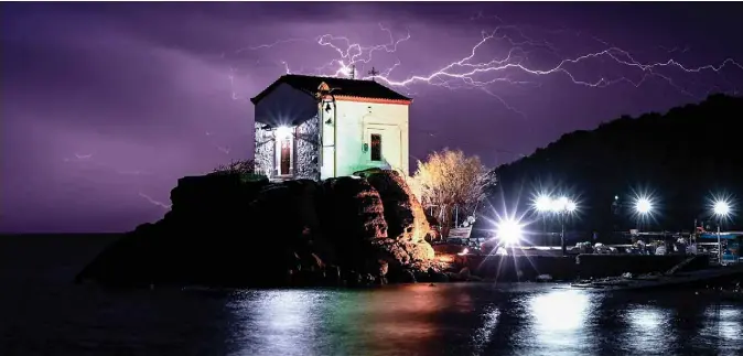  ??  ?? Lightning strikes behind the chapel of Panagia Gorgona in the village of Skala Sykamias, north of Lesbos, on February 27, 2020. — AFP