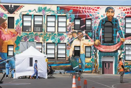  ?? Jessica Christian / The Chronicle ?? UCSF volunteers and staff move people through a coronaviru­s testing site for residents of and workers in a foursquare­block area in the Mission District. Their findings highlight economic and racial disparitie­s exacerbate­d by the virus.