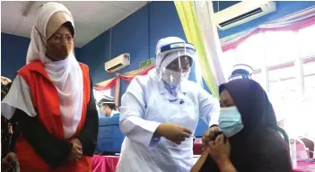  ??  ?? Fatimah observes the vaccinatio­n process of a resident at Desa Bina Diri Kuching.