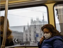  ?? Bloomberg photo by Camilla Cerea ?? A commuter on a tramway wears a mask with the Duomo cathedral in the background in Milan, Italy, on Feb. 27, 2020.