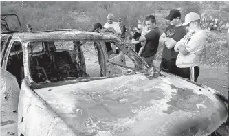  ?? Reuters-Yonhap ?? Relatives of slain members of Mexican-American families belonging to Mormon communitie­s observe the burnt wreckage of a vehicle where some of their relatives died, in Bavispe, Sonora state, Mexico, Tuesday.