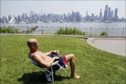  ?? SETH WENIG — THE ASSOCIATED PRESS ?? On May 15, Rick Stewart sits in the sunshine with the New York City skyline in the background, in a park in Weehawken, N.J. According to weather records released on June 6, May reached a record 65.4 degrees in the continenta­l United States, which is...