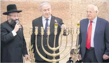  ?? AFP ?? Israeli Prime Minister Benjamin Netanyahu, centre, lights a Hanukkah candle at the Western Wall in Jerusalem.