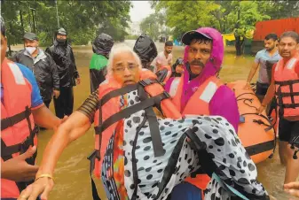  ?? Associated Press ?? A rescue worker saves an elderly woman stranded in floodwater­s in Kolhapur, in the western Indian state of Maharashtr­a. Landslides and flooding are common during the monsoon season.