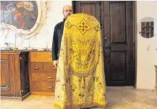 ?? FOTO: LEO SUCHAN ?? Der Zwiefalter Mesner Andreas Schäfer hält den schweren Rauchmante­l hoch, den der Pfarrer unter anderem auch an Ostern trägt.