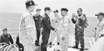  ??  ?? Rosales fourth left) shakes hands with Malvar onboard Tun Azizan Auxiliary vessel at the Lahad Datu water border. — Bernama photo