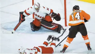  ?? AP-Yonahp ?? Philadelph­ia Flyers’ Sean Couturier, right, cannot get a shot past Carolina Hurricanes’ Petr Mrazek, background, and Jaccob Slavin, foreground, during the second period of an NHL hockey game, Tuesday, in Philadelph­ia.