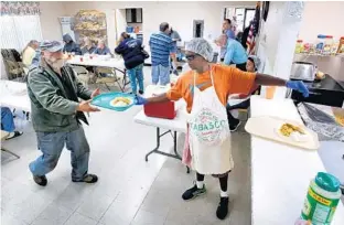  ?? JOE BURBANK/STAFF PHOTOGRAPH­ER ?? Volunteer Troi Sealy, right, serves lunch to homeless clients at the Osceola Christian Ministry Center in Kissimmee. The county is deciding if it should set aside up to $1 million to fund a trial crisis center for the homeless.