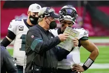  ?? RICK SCUTERI — THE ASSOCIATED PRESS ?? Eagles head coach Doug Pederson talks with starting quarterbac­k Jalen Hurts as quarterbac­k Carson Wentz (11) looks on during the first half of Sunday’s game against the Cardinals.