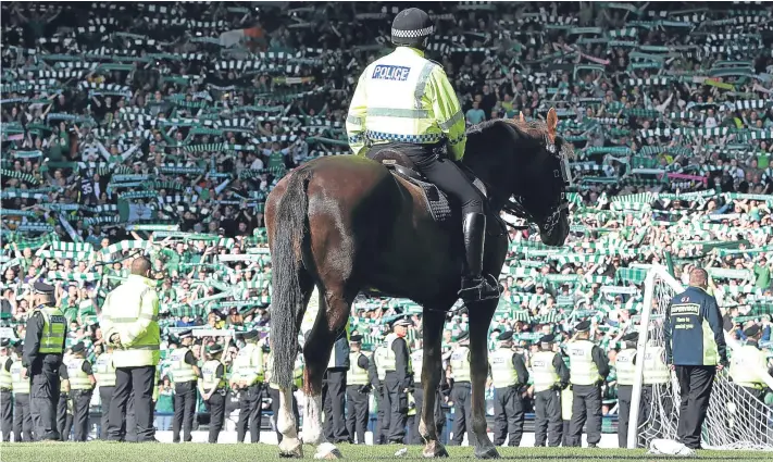  ?? Picture: Getty Images. ?? The scenes at the end of the Scottish Cup Final as Hibernian fans are held in by mounted police after invading the pitch following their team’s win.