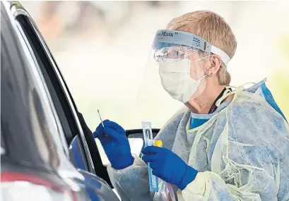  ?? NATHAN DENETTE THE CANADIAN PRESS FILE PHOTO ?? Health-care workers do testing at a drive-thru COVID-19 assessment centre at the Etobicoke General Hospital in early April.