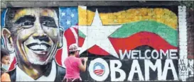  ?? ASSOCIATED PRESS ?? A woman takes a photo Saturday in Yangon, Myanmar, of a wall painting created by Myanmar graffiti artists to welcome President Barack Obama. Obama will visit the Asian nation on Monday, a first for a sitting U. S. president.