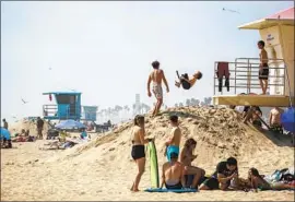  ?? Allen J. Schaben Los Angeles Times ?? KIDS PLAY as others relax on the sand Thursday, the last day of open beaches in Huntington Beach after the governor announced a “hard close” in Orange County.