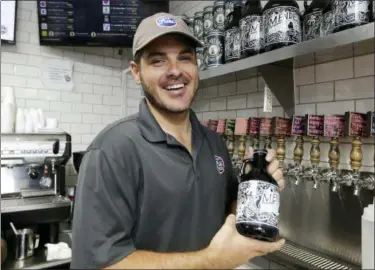  ?? LYNNE SLADKY — ASSOCIATED PRESS ?? Manager Andrew Mendez holds a beer growler for craft beer sold at the Mendez Fuel convenienc­e store in Miami last month.