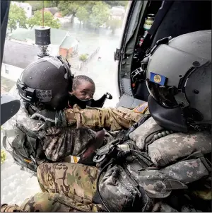  ?? AP/Omaha World-Herald/CHRIS MACHIAN ?? Staff Sgt. Lawrence Lind (left) and Sgt. Ray Smith of the Nebraska National Guard hoist a child into their Black Hawk helicopter during rescue operations Wednesday in Port Arthur, Texas.