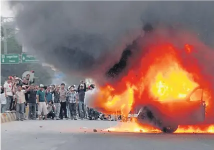  ?? EPA ?? Cambodians watch as a police car is set on fire at an election polling station in Phnom Penh yesterday. Cambodian voters angry that they could not find their names on the voters list overturned a police car and set it on fire. Police reportedly fired...