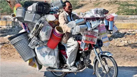  ?? — APP ?? SHOP ON WHEEL: A vendor rides his bike loaded with household items on the Larkana-Sukkur Road to sell them in Larkana on Tuesday.