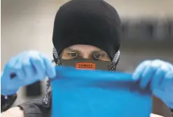  ??  ?? Micah Cash sews a face mask using a San Jose Sharks Tshirt at the Timbuk2 factory. The masks will be donated to community groups.