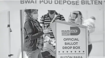  ?? DAVID SANTIAGO dsantiago@miamiheral­d.com ?? A 2020 photo of a poll worker depositing ballots at a drop box outside the Westcheste­r Regional Library.