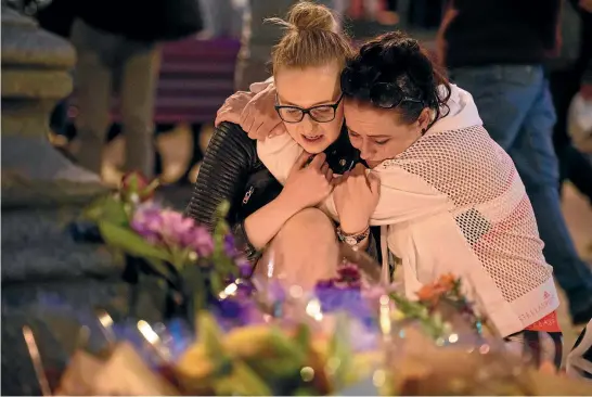  ?? PHOTO: GETTY IMAGES ?? A woman is consoled as she looks at the floral tributes following an evening vigil outside the Town Hall in Manchester.