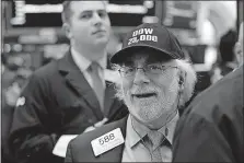  ?? [RICHARD DREW/THE ASSOCIATED PRESS] ?? Trader Peter Tuchman wears a “Dow 23,000” hat as he works on the floor of the New York Stock Exchange. The Dow Jones index hit that number Wednesday for the first time in history.