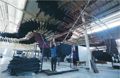  ??  ?? WORKERS CARRY leather in the factory of Al-Rowad Tannery at Robiki Leather City, near Cairo, last week.