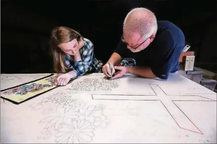  ?? CURTIS COMPTON/CCOMPTON@AJC.COM ?? While daughter Lauren Clamp watches, Mart Clamp uses a precision knife to cut a stencil for the memorial he is making for his father, who, like his father before him, worked in the granite industry in Elberton.