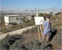  ?? PHOTO: REUTERS ?? Hanna Horowitz, a resident of the Jewish settler outpost of Amona in the West Bank, works on a painting near a settler’s caravan yesterday.