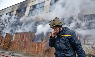  ?? AP PHOTO/LIBKOS ?? A Ukrainian State Emergency Service firefighte­r takes a break Sunday following Russian shelling that hit an industrial area in Kherson, Ukraine.