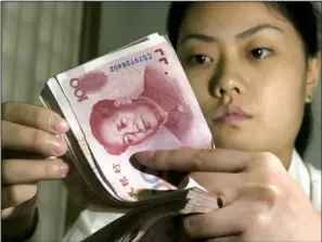  ??  ?? MONEY MOVES: A Chinese bank worker displays Chinese yuan at a bank in Beijing,