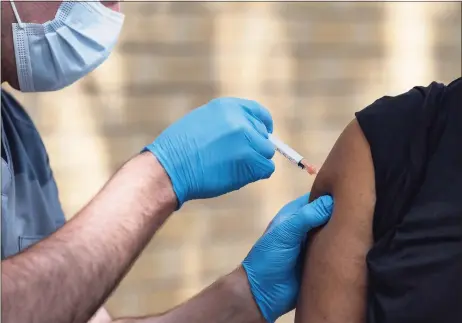  ?? Associated Press ?? National Guard Spc. Noah Vulpi, left, administer­s the Johnson & Johnson COVID-19 vaccine to Ira Young Jr. during a vaccinatio­n clinic held by the National Guard in Odessa, Texas, in May. Larger U.S. businesses won't have to decide whether to require their employees to get vaccinated against COVID-19. Doing so is now federal policy, although many of the details have yet to be worked out. President Joe Biden announced sweeping new orders Thursday that will require employers with more than 100 workers to mandate immunizati­ons or offer weekly testing.