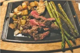  ?? PHOTOS BY MEGHAN MANGRUM ?? The Butcher’s Butter Steak at State of Confusion is plated on a cast-iron serving platter alongside Confusion Potatoes — a medley of white, red and sweet potatoes cubed, seasoned and cooked in a skillet with green peppers and either seasonal vegetables or grilled asparagus.