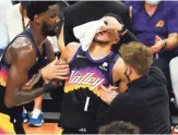  ??  ?? Suns guard Devin Booker (1) receives treatment after being cut by Clippers guard Patrick Beverley (not pictured) Tuesday.