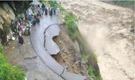  ??  ?? NATURE’S FURY: Residents and travelers stand on the remains of a flood-damaged road in the state of Uttarakhan­d. (AFP)