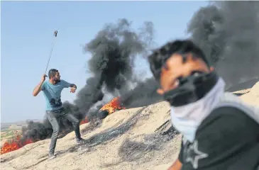  ??  ?? FRESH FIGHTING: A Palestinia­n protester hurls stones towards Israeli troops near the border between Israel and the central Gaza Strip on Friday.