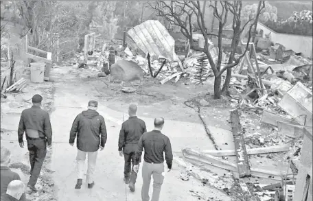  ?? Photograph­s by Genaro Molina Los Angeles TImes ?? PRESIDENT TRUMP, second from left, is accompanie­d by first responders on Saturday as he tours parts of Malibu devastated by recent wildfires. He seemed shocked as he visited the charred landscapes of the Camp and Woolsey fires, which have killed more than 70 people.