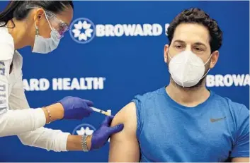  ?? JOE RAEDLE/GETTY ?? Leonida Lipshy, a nurse in the COVID-19 unit at the Broward Health Medical Center, gives Dr. Nadav Fields, a D.O. of internal medicine at Broward Health Imperial Point, the Moderna vaccine on Wednesday in Fort Lauderdale.