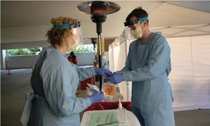  ??  ?? Nurses wearing protective clothing handle a bag with a potentiall­y infected coronaviru­s swab at a drive-through testing center in Seattle, Washington. Photograph: John Moore/Getty Images