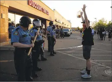  ?? John Minchillo Associated Press ?? A PROTESTER faces police officers in St. Paul, Minn. In addition to denouncing the killing of George Floyd, police chiefs should call for the prosecutio­n of Minneapoli­s Police Officer Derek Chauvin, activists say.