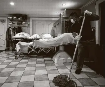  ?? Godofredo A. Vásquez / Staff file photo ?? Manuel Santos mops the floor at Houston’s Compean Funeral Home, where eight of the 10 bodies being prepared for services on Aug. 5 were of COVID-19 victims.