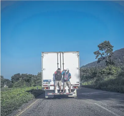  ?? Pedro pardo/aFp ?? Dos migrantes avanzan en la caravana montados a un camión