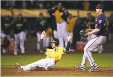  ?? Ben Margot / Associated Press ?? Stephen Piscotty slides home with the winning run in front of Twins reliever Trevor Hildenberg­er, who uncorked a wild pitch with two outs in the bottom of the ninth inning.